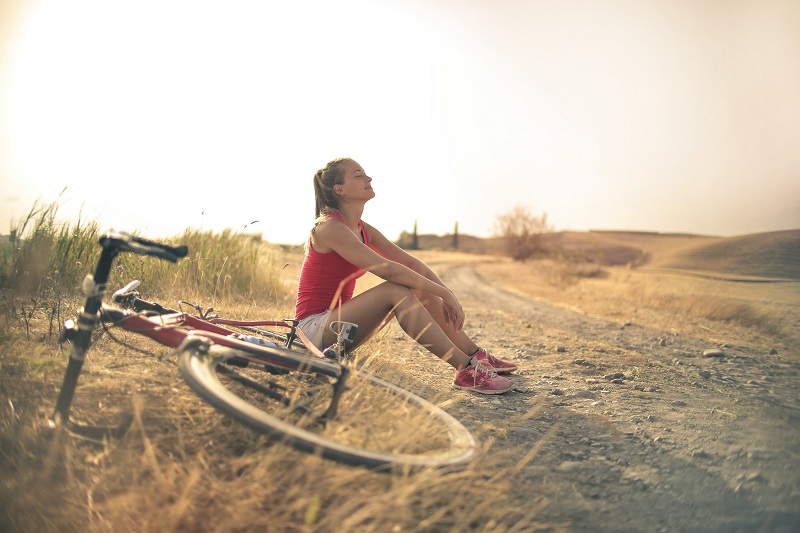 Top 5 States for Biking Trails Woman Sitting on the Side of a Trail with a Bike