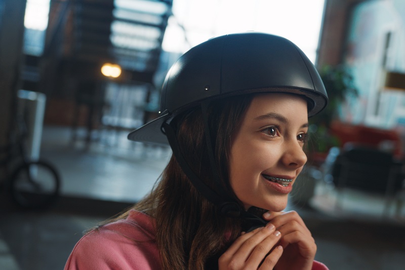 Why ProLids Helmets were Invented Young Girl Smiling as She Puts on a ProLids Helmet