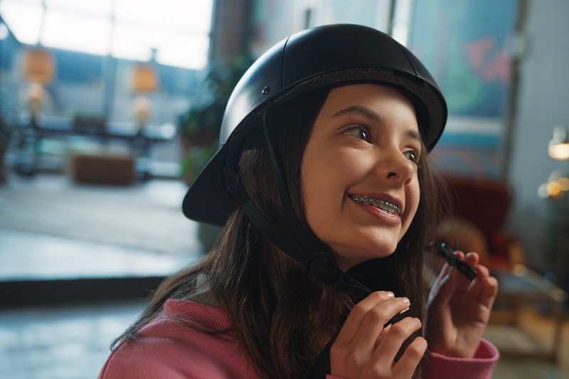 How to Find the Right Fit for Your Bike Helmet a Young Girl Adjusting the Straps on Her Helmet