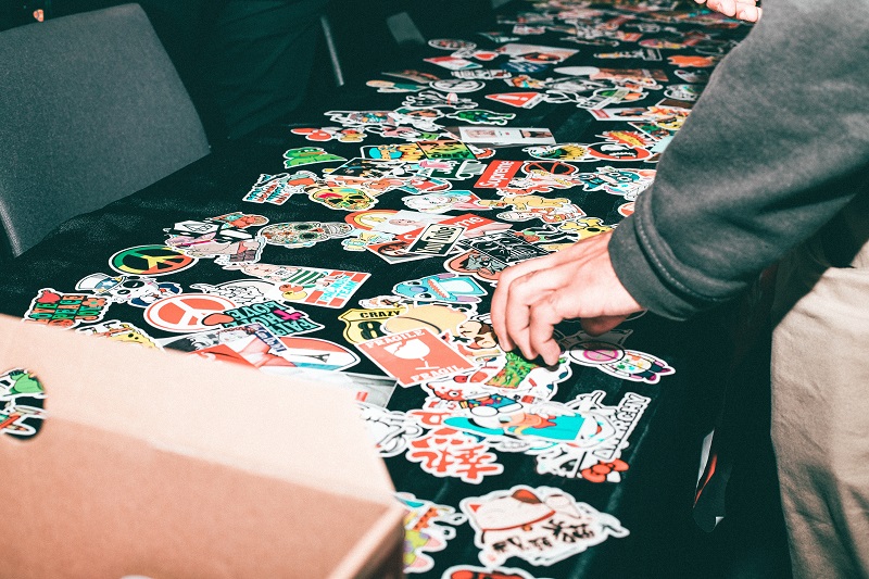 How to Personalize your ProLids Helmet a Table Covered with Different Stickers to Pick with a Person's Hand Reaching for One of the Stickers