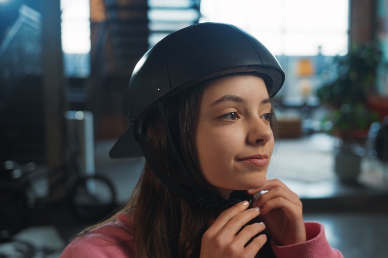 Helmet Strap Features a Young Girl Connecting the Buckle of a ProLids Helmet