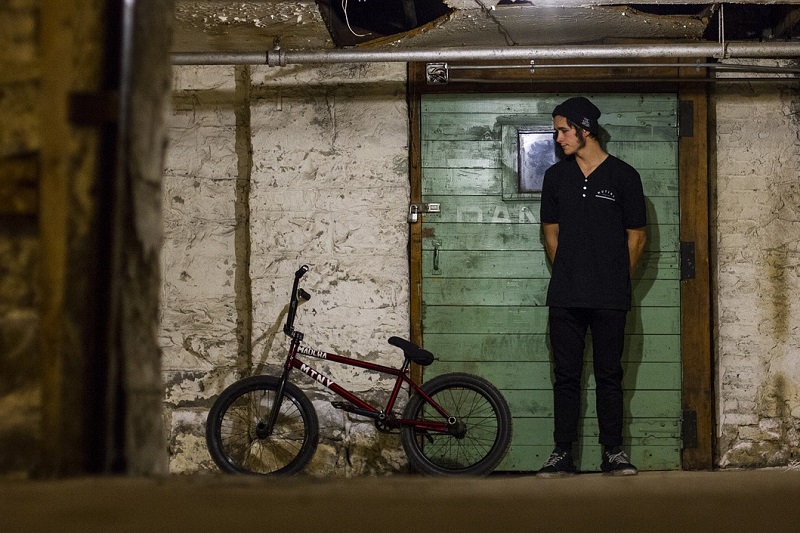 Tips for Picking the Right BMX Bike a Rider Standing Against a Wall Next to a BMX Bike Leaning Against the Same Wall