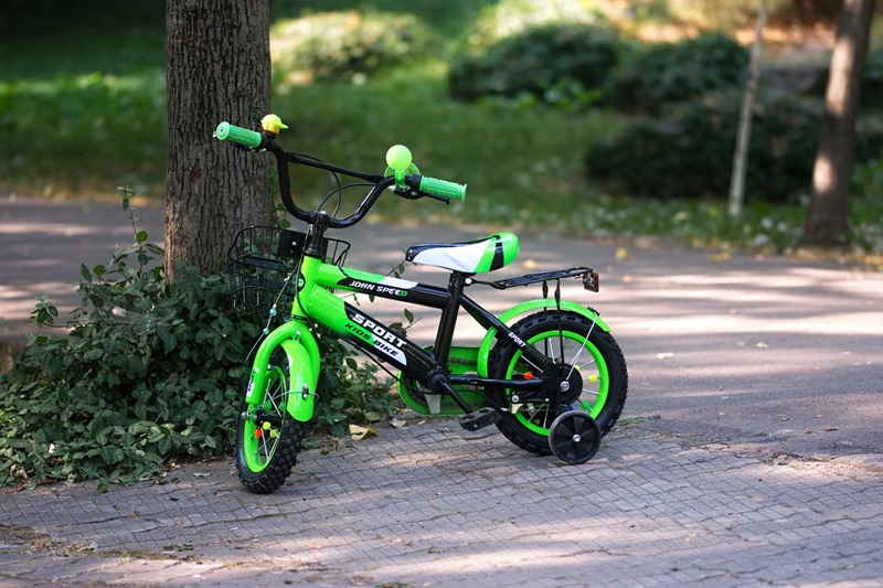 How to Size a Bike for Your Child Close Up of a Green Bike with Training Wheels Sitting Next to a Tree