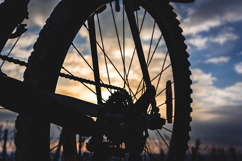 What to Look for When Sizing a Bike Chain Silhouette of a Bike Tire with the Sun Setting Behind It