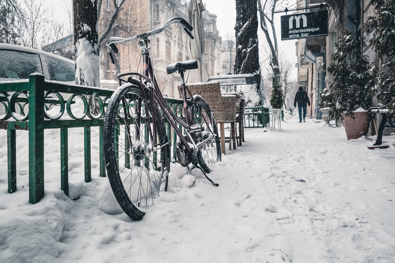 Bike Safety Tips for Cooler Weather a Bike Leaned Up Against a Fence with Snow on the Ground