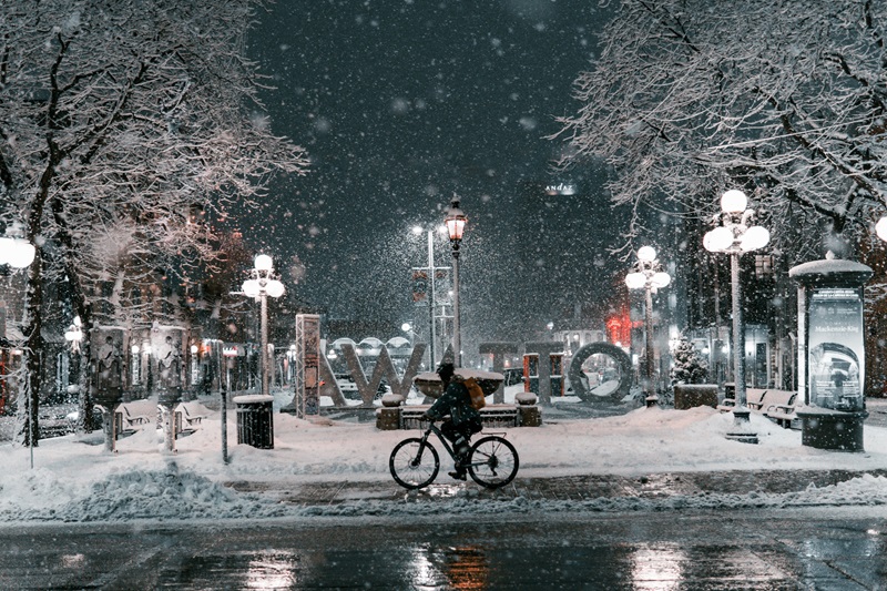 Bike Safety Tips for Cooler Weather a Person Riding a Bike at Night While it is Snowing