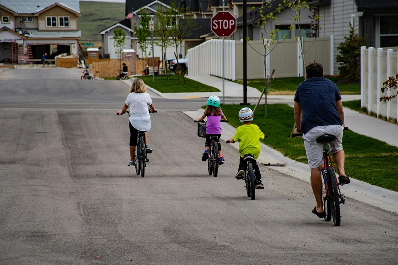 Riding a Bike to School Advantages and Disadvantages for Kids a Family with Two Kids Riding Bikes Down a Street in a Suburb