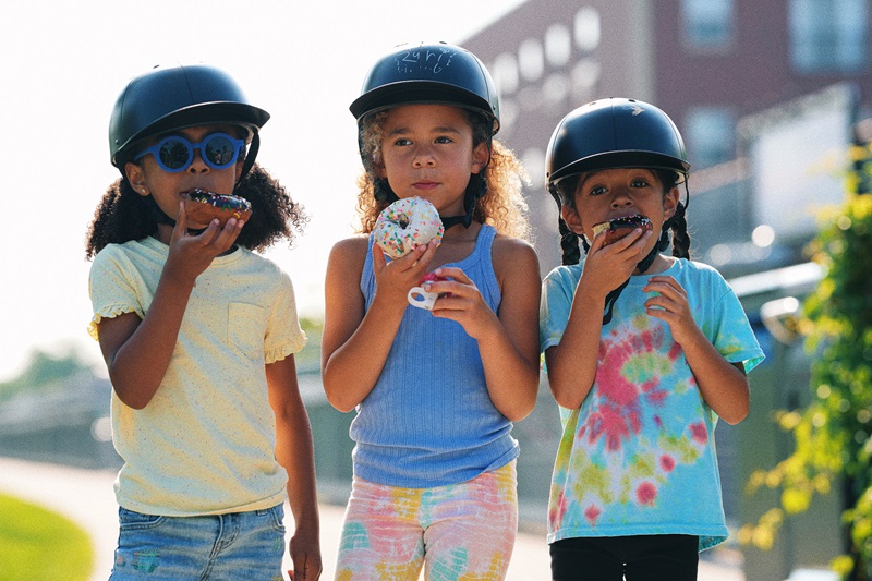Why ProLids Interchangeable Brims are Perfect for Kids Three Young Girls Standing Together Wearing ProLids Helmets Outdoors Eating Donuts