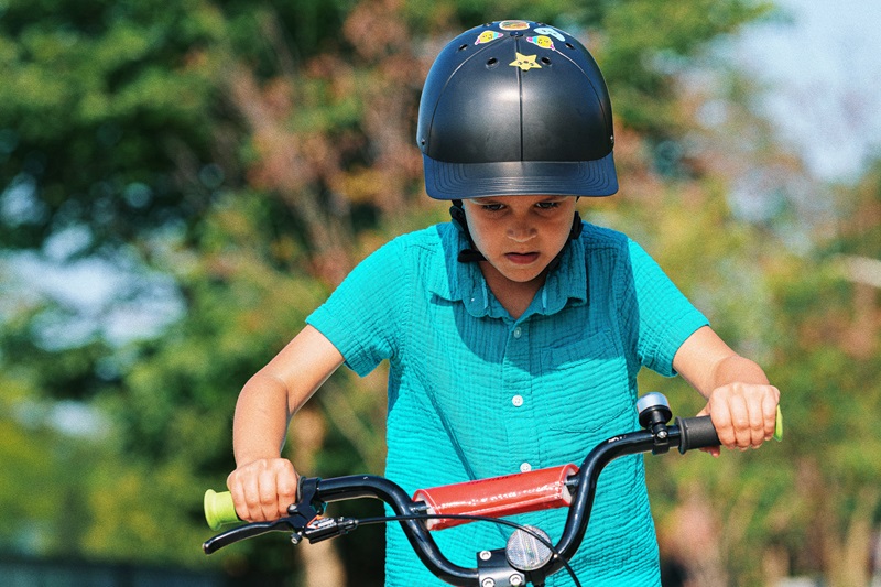Most Important Summer Bike Safety Tips a Young Boy Wearing a ProLids Helmet Riding a Bike Outside