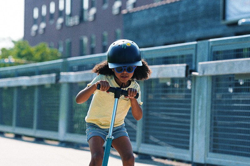 Most Important Summer Bike Safety Tips a Young Girl Wearing a ProLids Helmet Riding a Scooter Outside