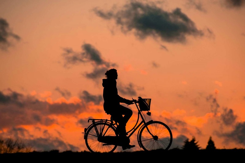 Best Bike Trails in Oregon Silhouette of a Person on a Bike with the Sun Setting Behind Them
