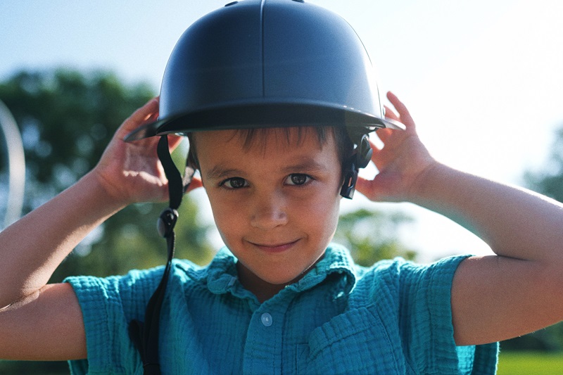 Types of Helmets for Kids Young Boy Putting on a ProLids Helmet