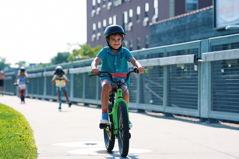 When to Replace a Helmet a Child Wearing a Helmet Riding a Bike Along a Paved Pathway