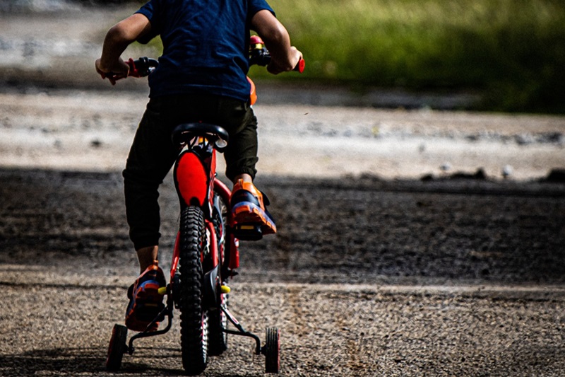 Best Bike Trails for Kids in Austin Close Up of a Young Boy Riding a Bike with Training Wheels Attached